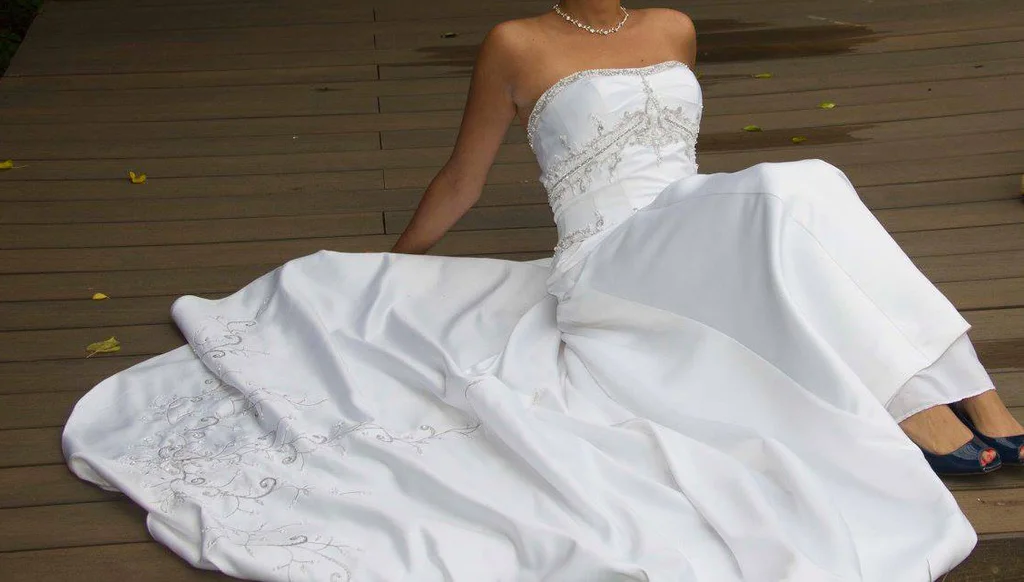 white A-line gown featuring a fitted, subtly ruched bodice with intricate beaded or embroidered detailing at the empire waist.